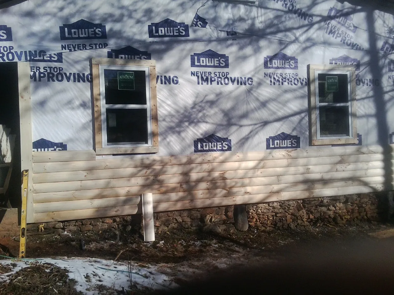 House wrap and new log siding going up on an exterior wall in Elmwood