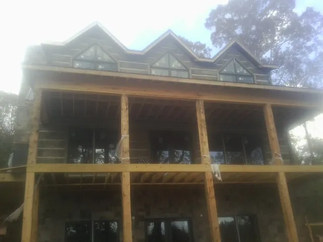 Dormers and porch framing on a large log home under construction — Roof Coating work by our crew in Elmwood