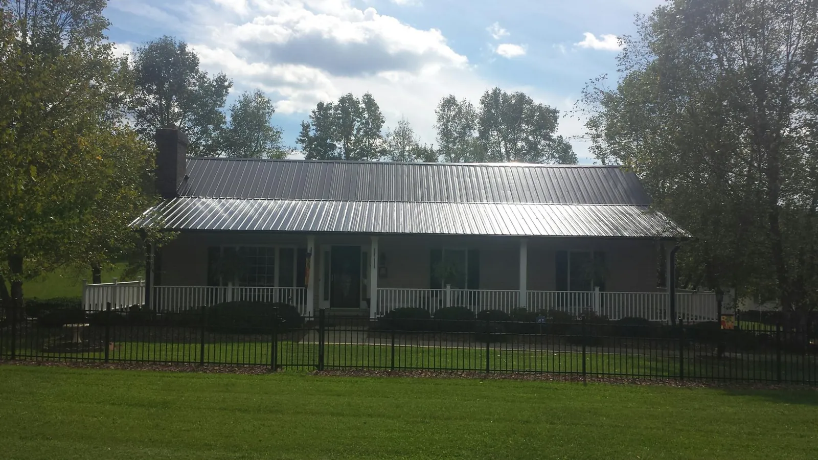 Gray metal roof on a brick ranch with a full width front porch — Gutter Guard Installation work by our crew in Elmwood