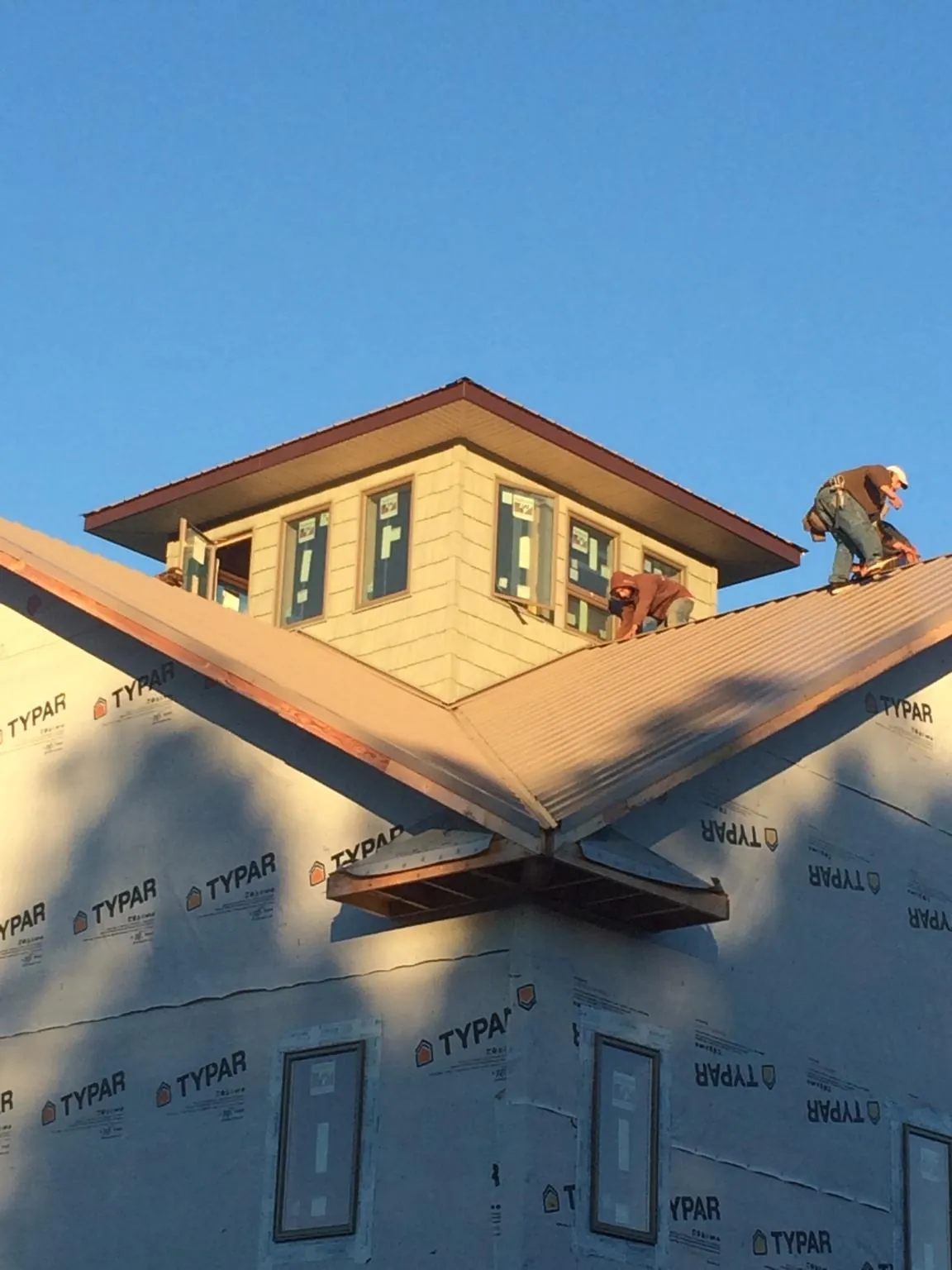 Roofers working around a rooftop cupola on a new metal roof at sunset — Roof Waterproofing in Elmwood by Roofing Brothers